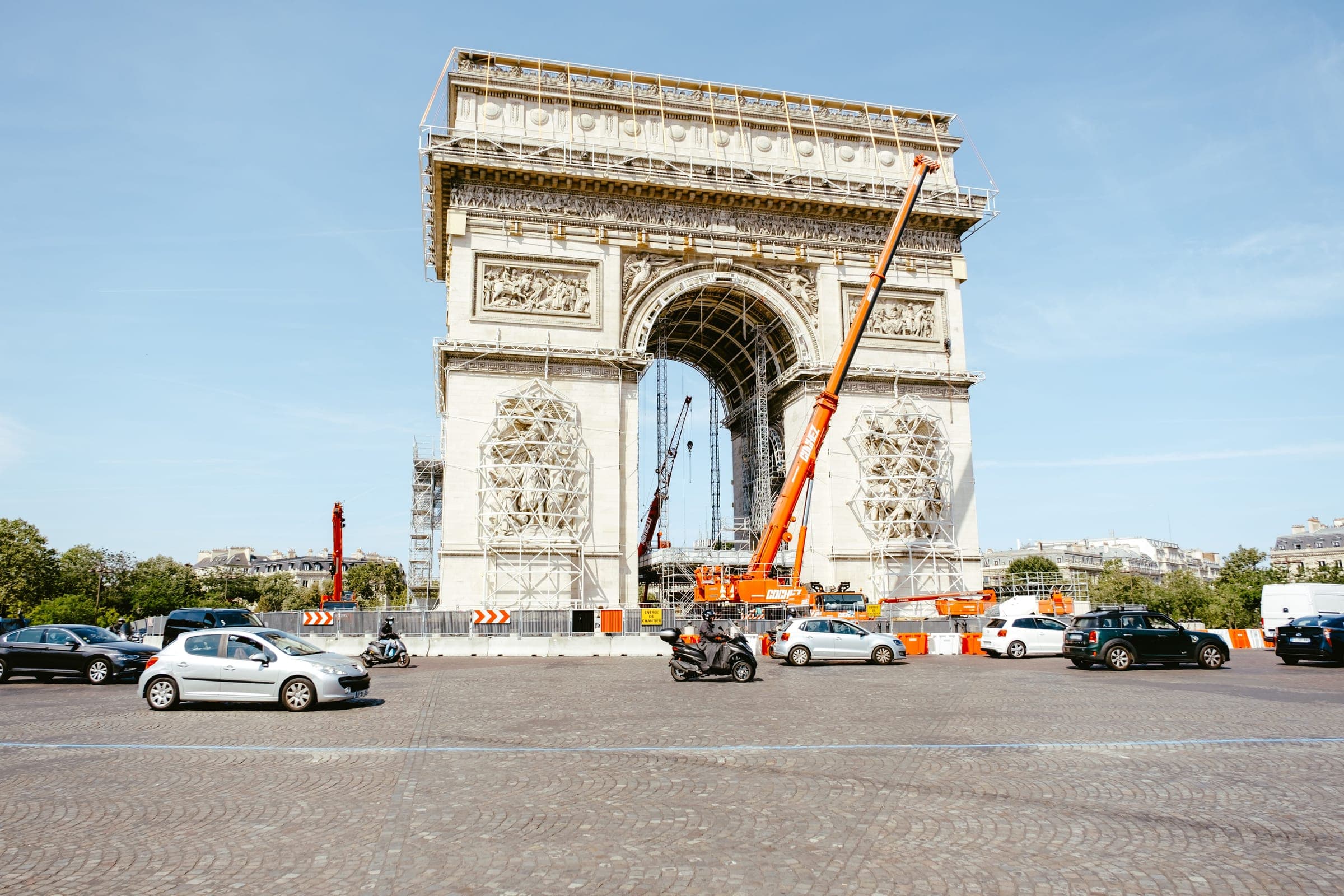 Grue mobile orange déployée le long de l'Arc de Triomphe en cours de rénovation, à Paris.