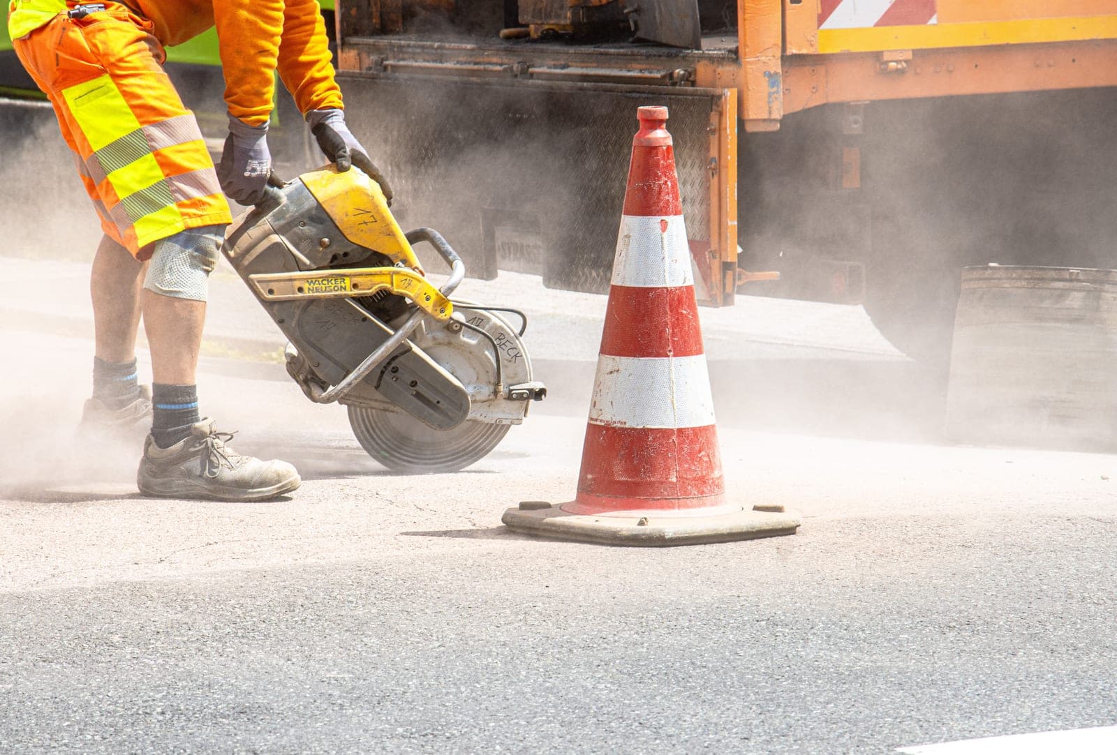 Découpe d'un enrobé de chaussée à la scie thermique, un poste de travaux de voirie chiffré à part dans un devis.